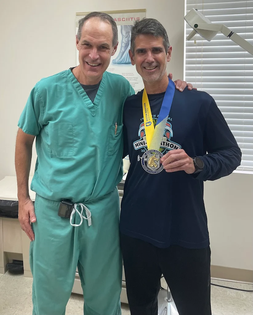 Dr. William Johncock with a runner patient holding a race medal